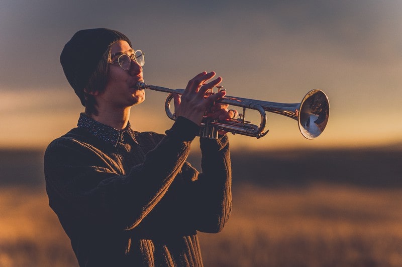 A young man playing a trumpet outside