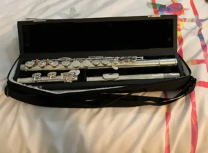 a Pearl alto flute within a flute case laying on a bed