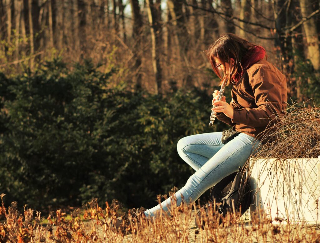 A young girl playing the flute outdoors