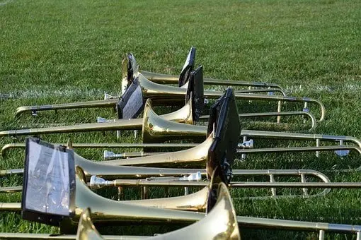 Several marching band trombones laying on a green field